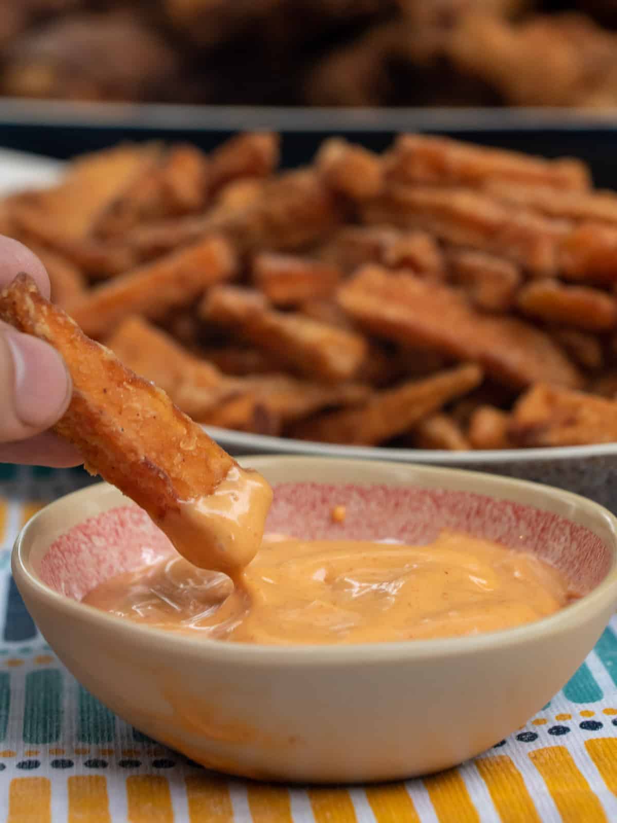 Sweet potato fry being dipped into spicy ranch.