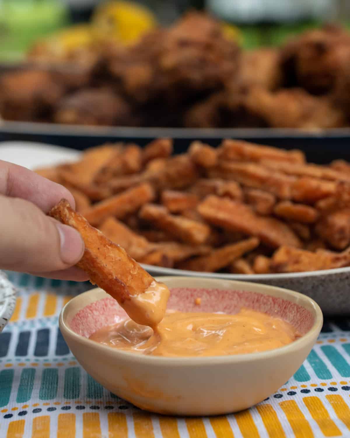 A fry being dipped into a small bowl of spicy ranch.