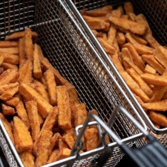Two fry baskets full of sweet potato fries.