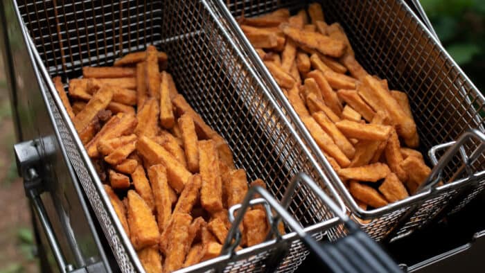 Two fry baskets full of sweet potato fries.