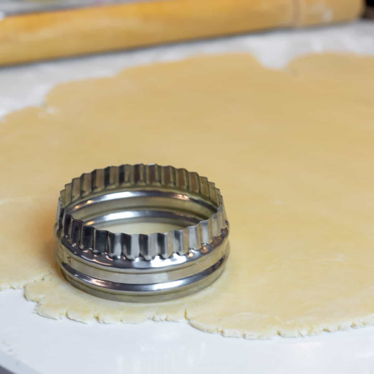 Cutting a circle out of rolled pastry dough.