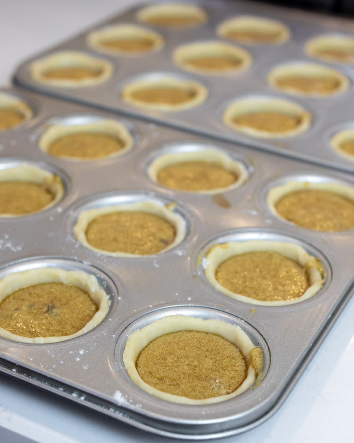 Muffin tin filled with raw tarts.