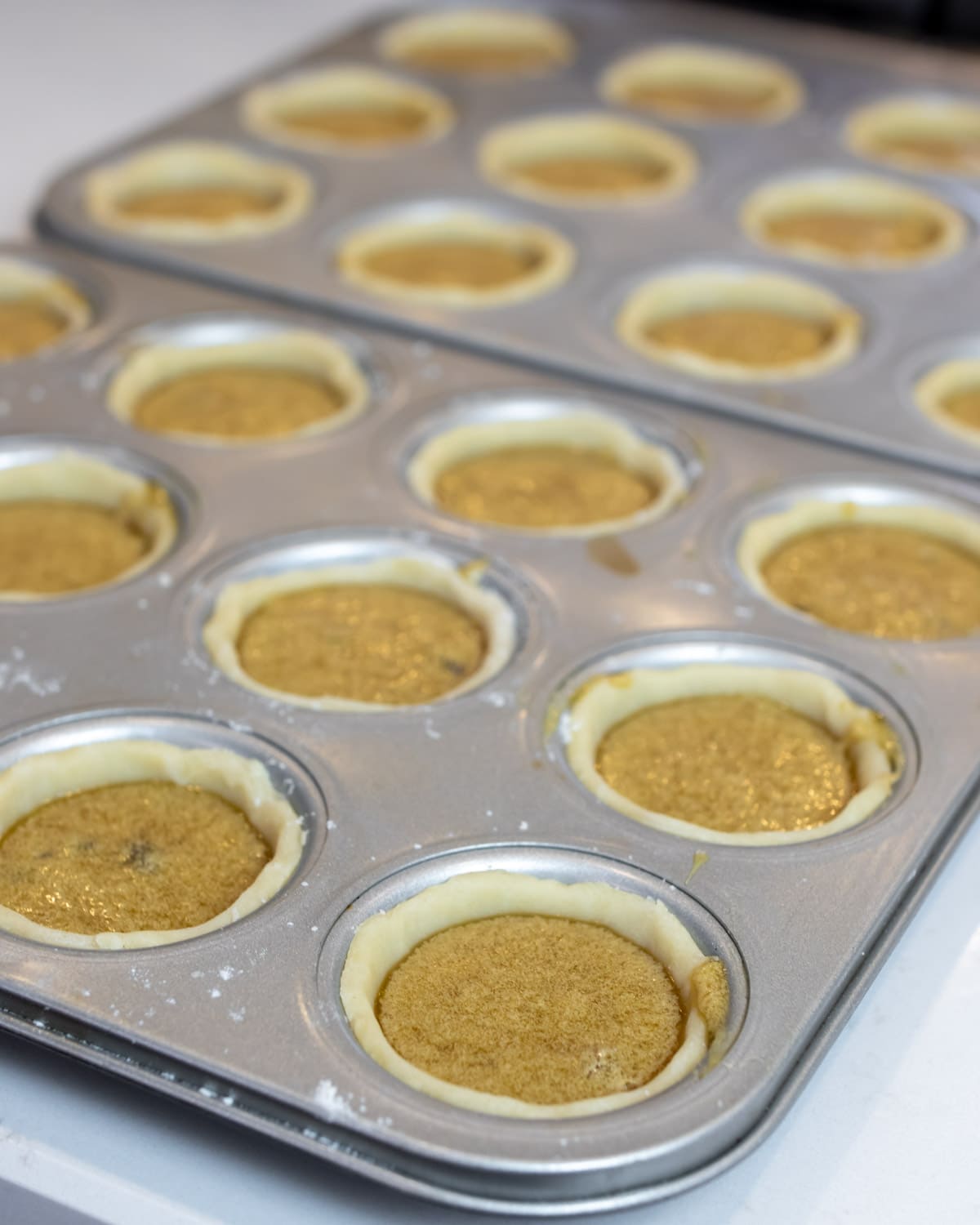 Muffin tin filled with raw tarts.