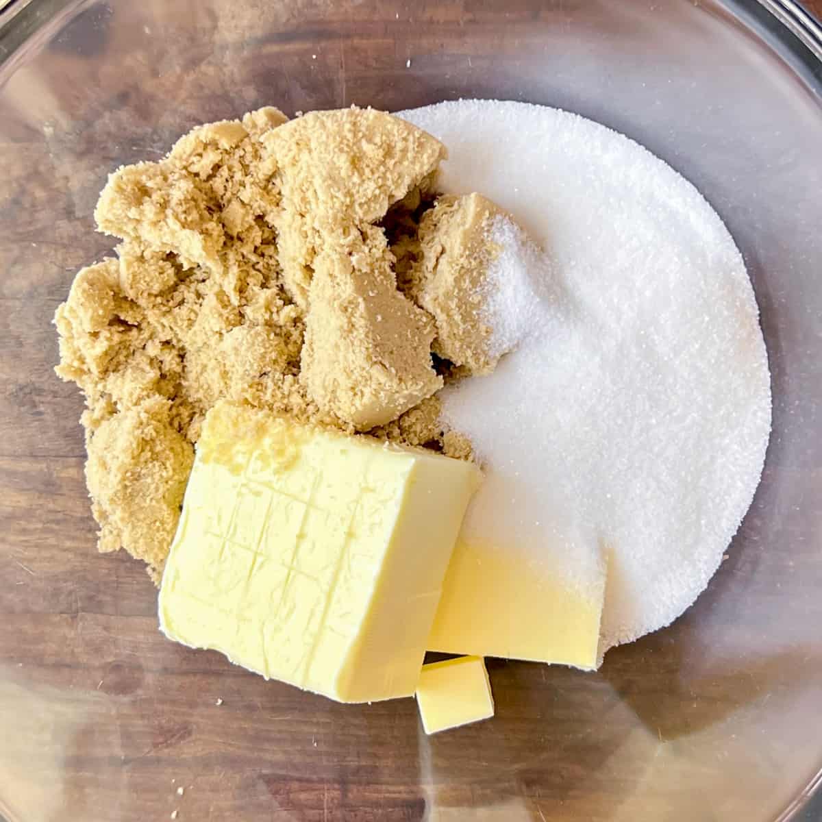 A glass bowl with butter, white sugar and brown sugar.