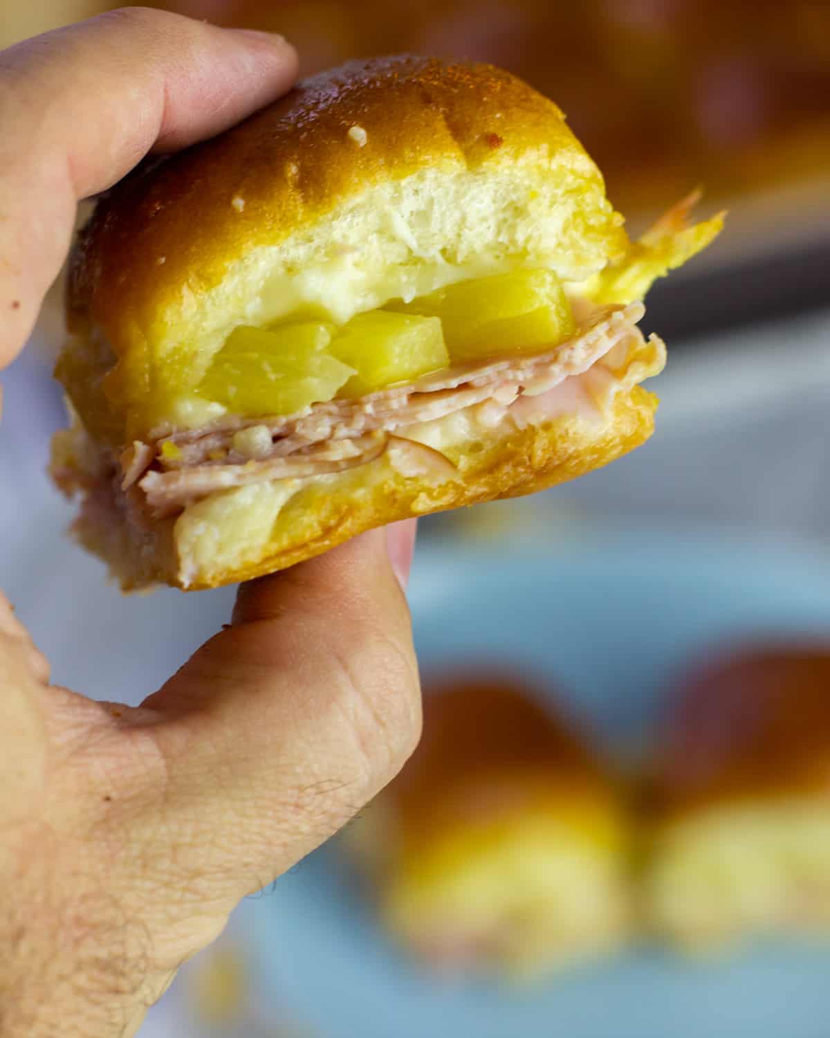 A slider being held in a hand over a plate.