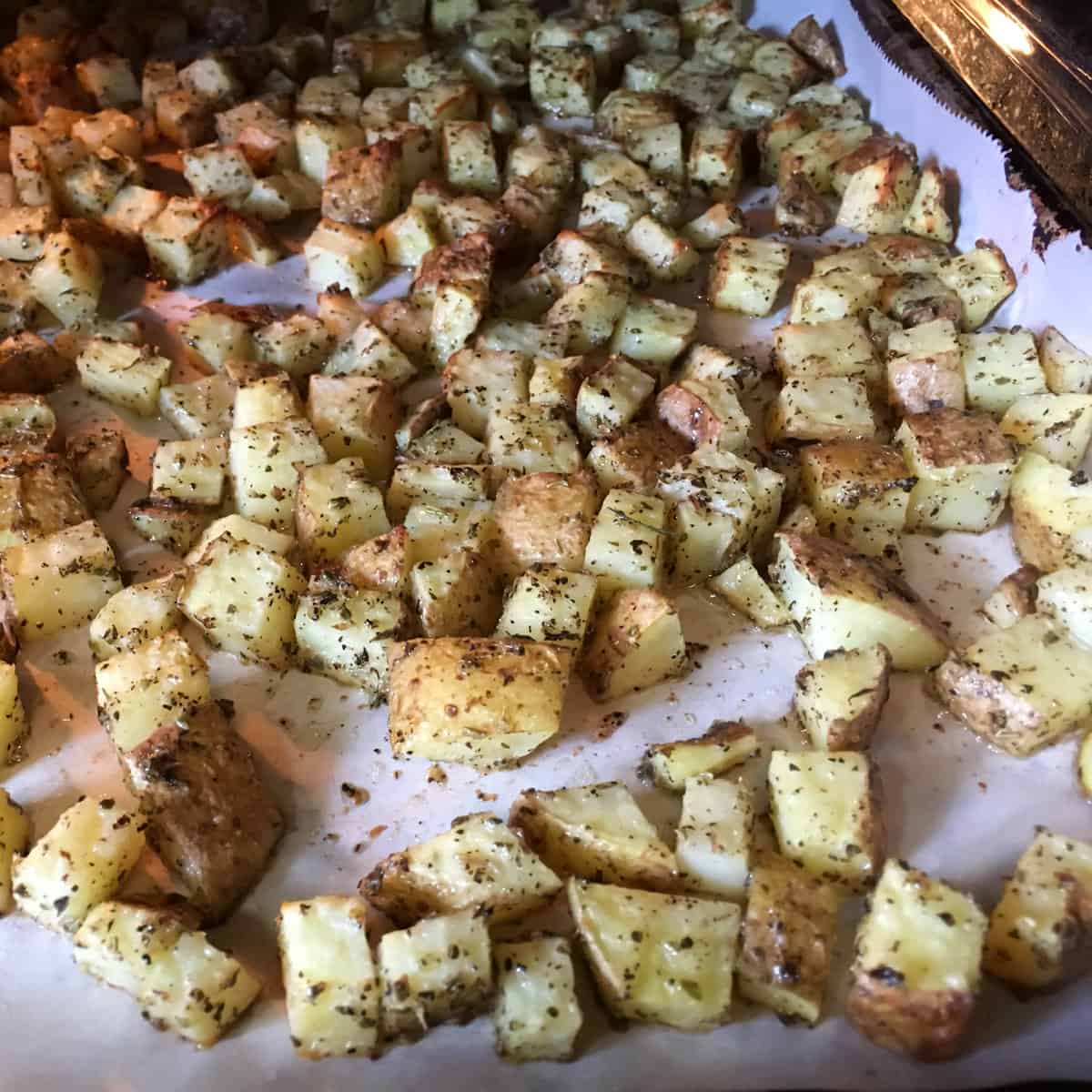 Potatoes with seasoning on a baking sheet.