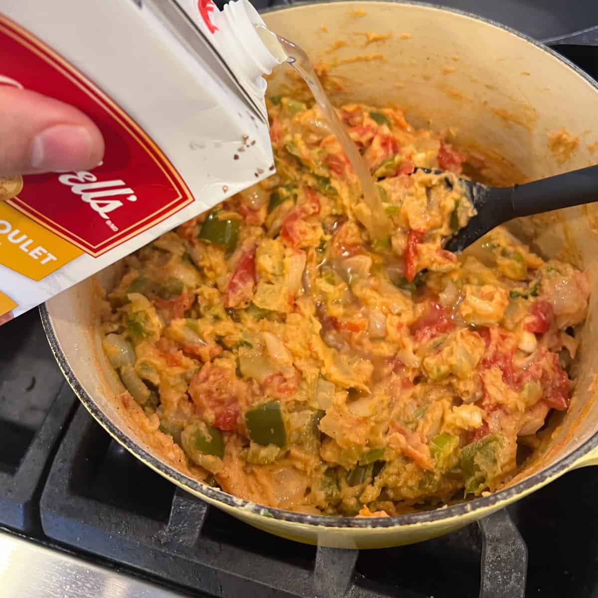 Pouring broth into the cooked vegetables.