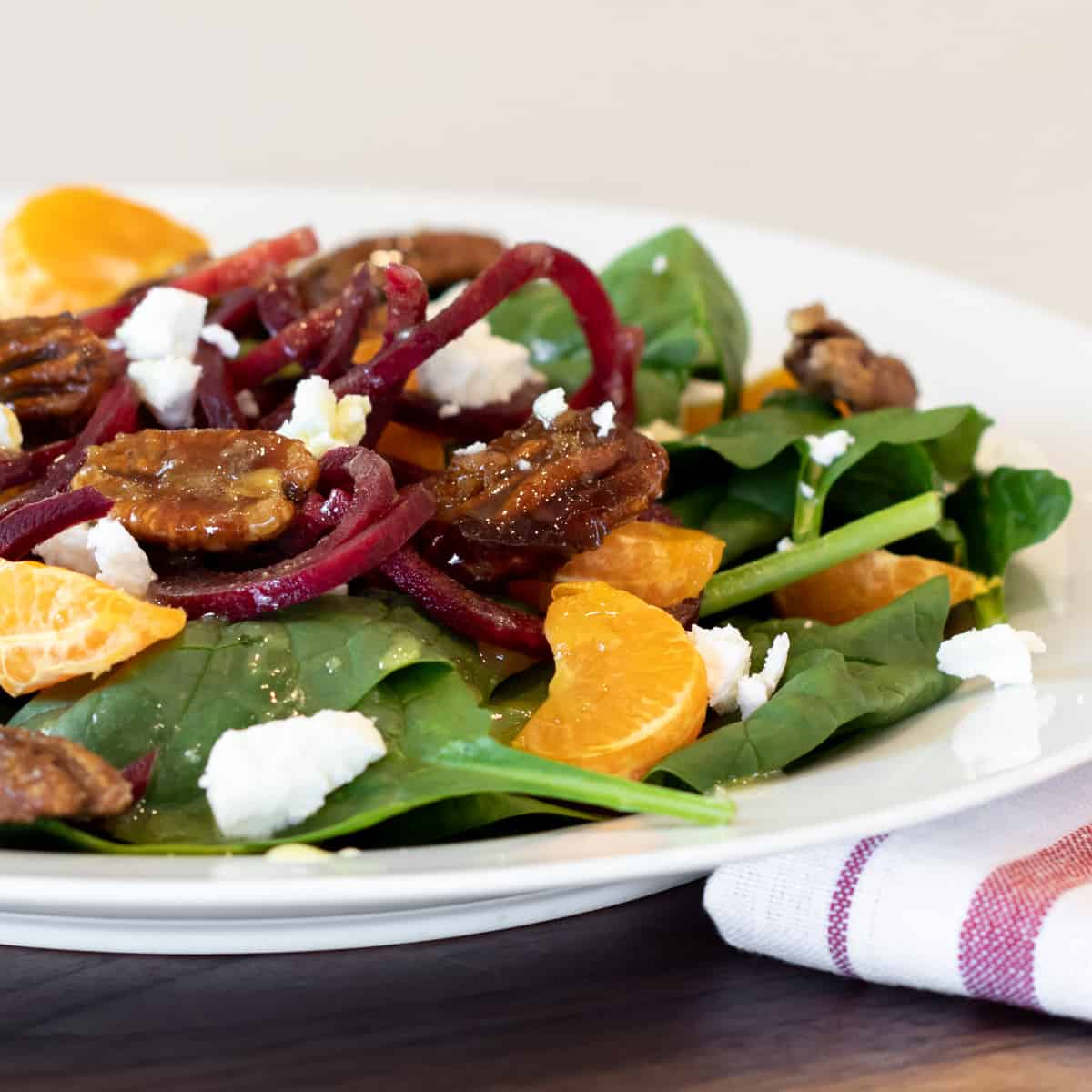 Close up picture with salad that has oranges and pecans.