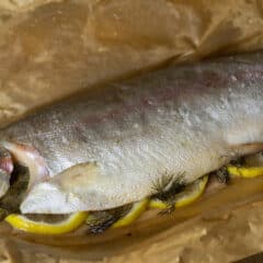 A cooked whole trout on a sheet of parchment paper.