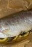 A cooked whole trout on a sheet of parchment paper.