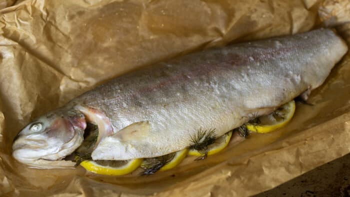 A cooked whole trout on a sheet of parchment paper.