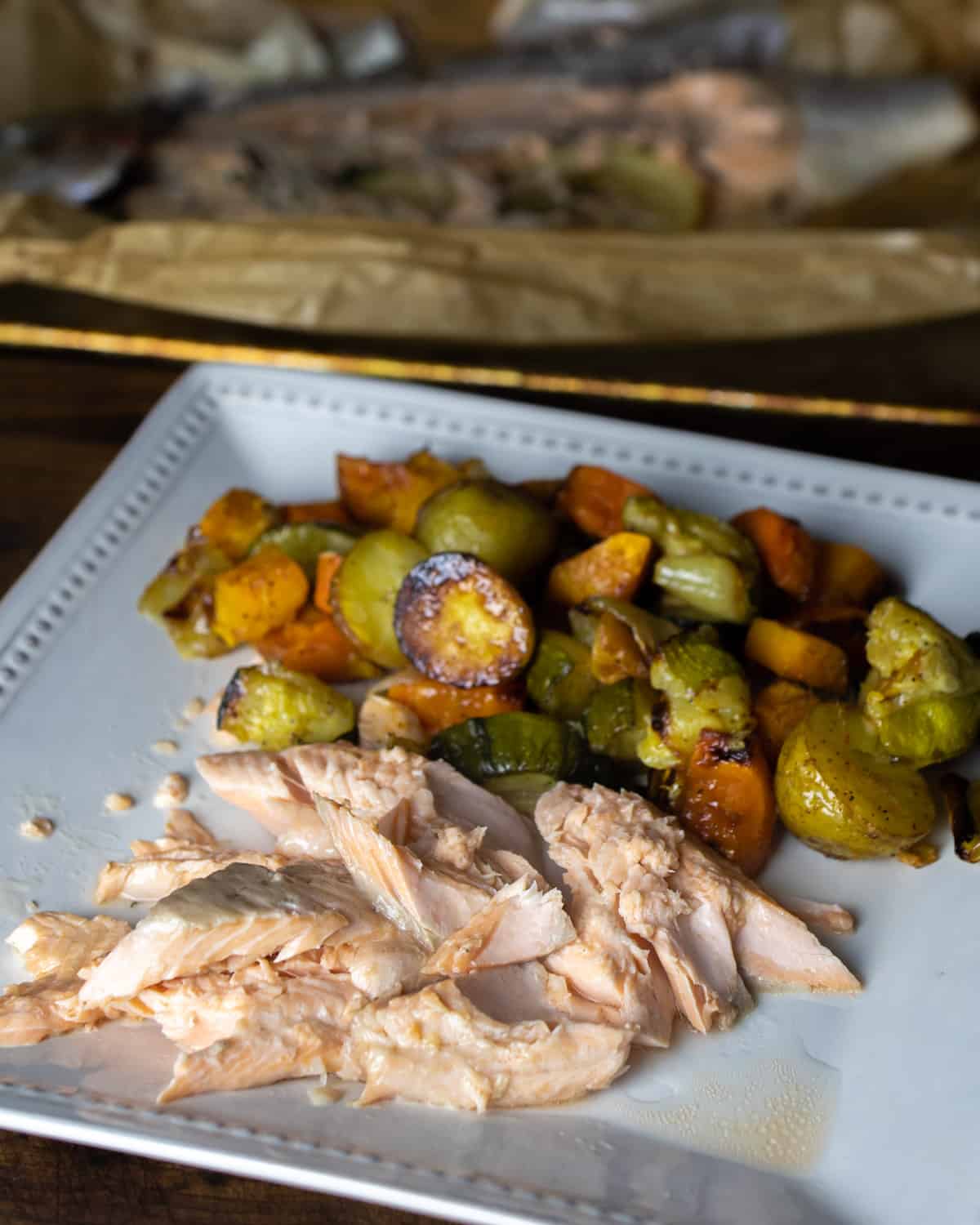 Piece of fish on a plate with roasted vegetables.