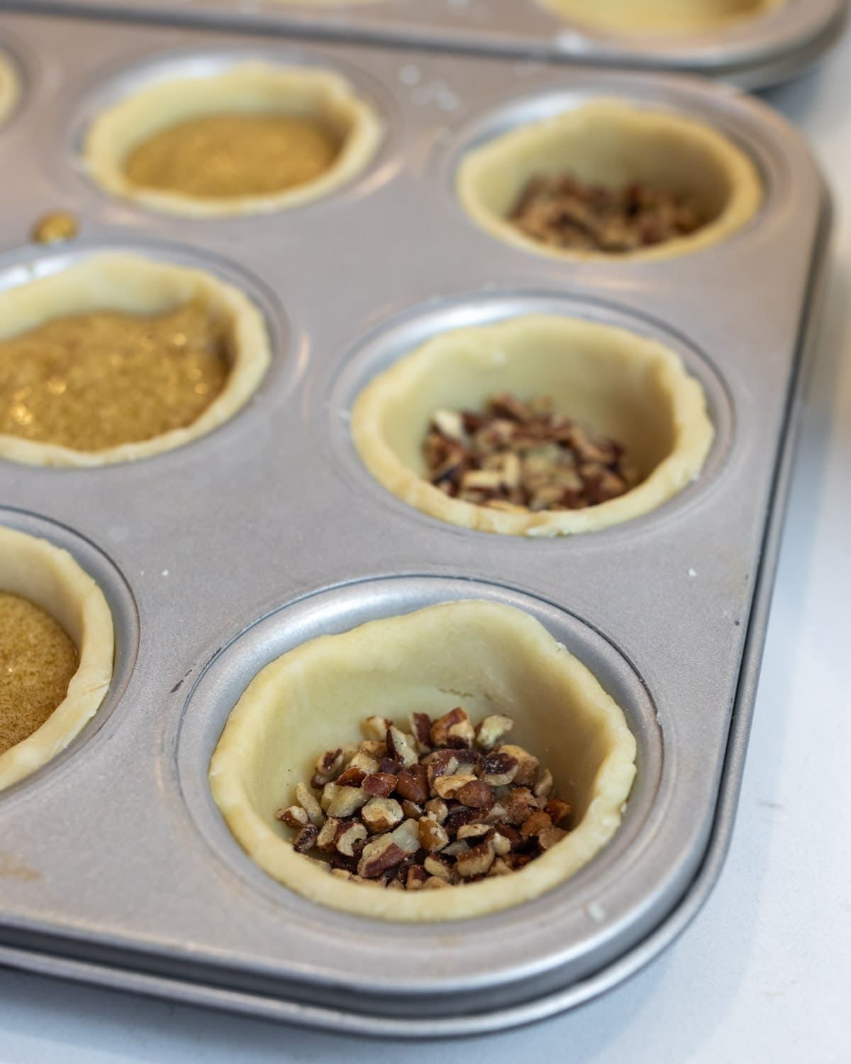 Chopped pecans at the bottom of a tart shell.