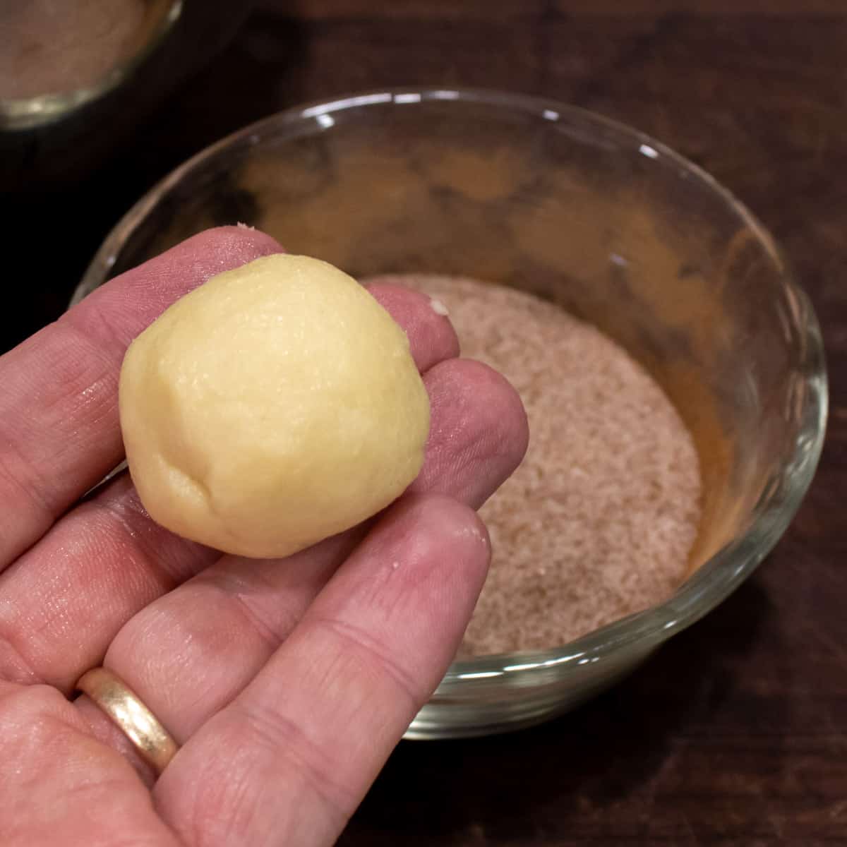 Cookie dough shaped into a small ball being held in a hand.