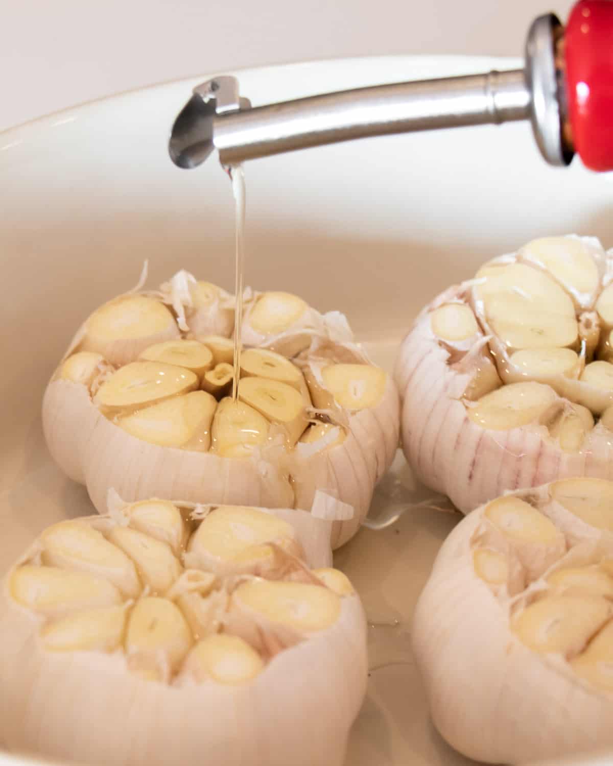 Oil being poured out of a cruet and drizzled on garlic.