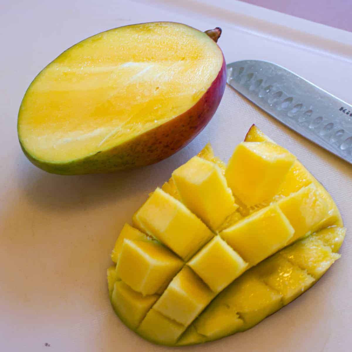 Mango cut in half on a cutting board.