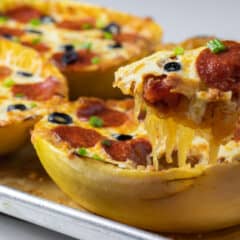 Scooping some filling out of a baked squash.