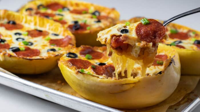 Scooping some filling out of a baked squash.