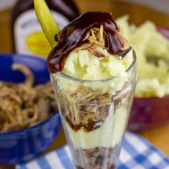 Pulled pork parfait in front of bowls of pork and mashed potatoes.