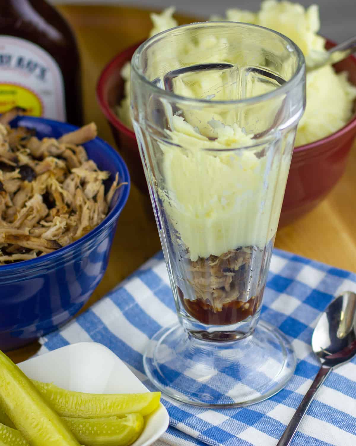 A sundae bowl with bbq sauce and potatoes added to the bottom.