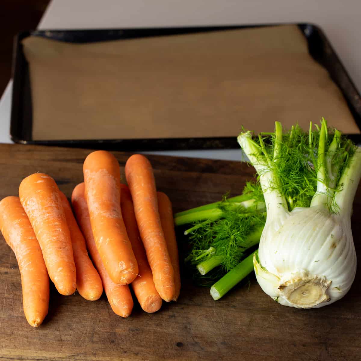 A pile of carrots and fennel on a cutting board.