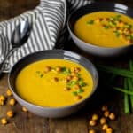 Two bowls of soup with a napkin and spoon.