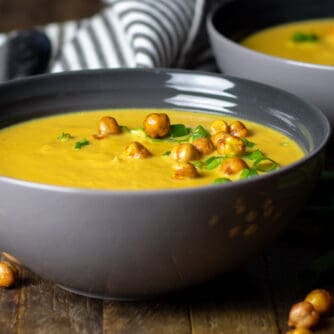 A bowl of soup with chick peas as a garnish.