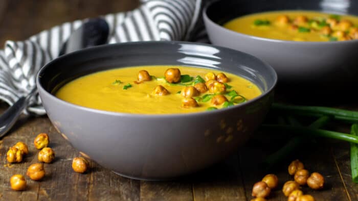 A bowl of soup with chick peas as a garnish.