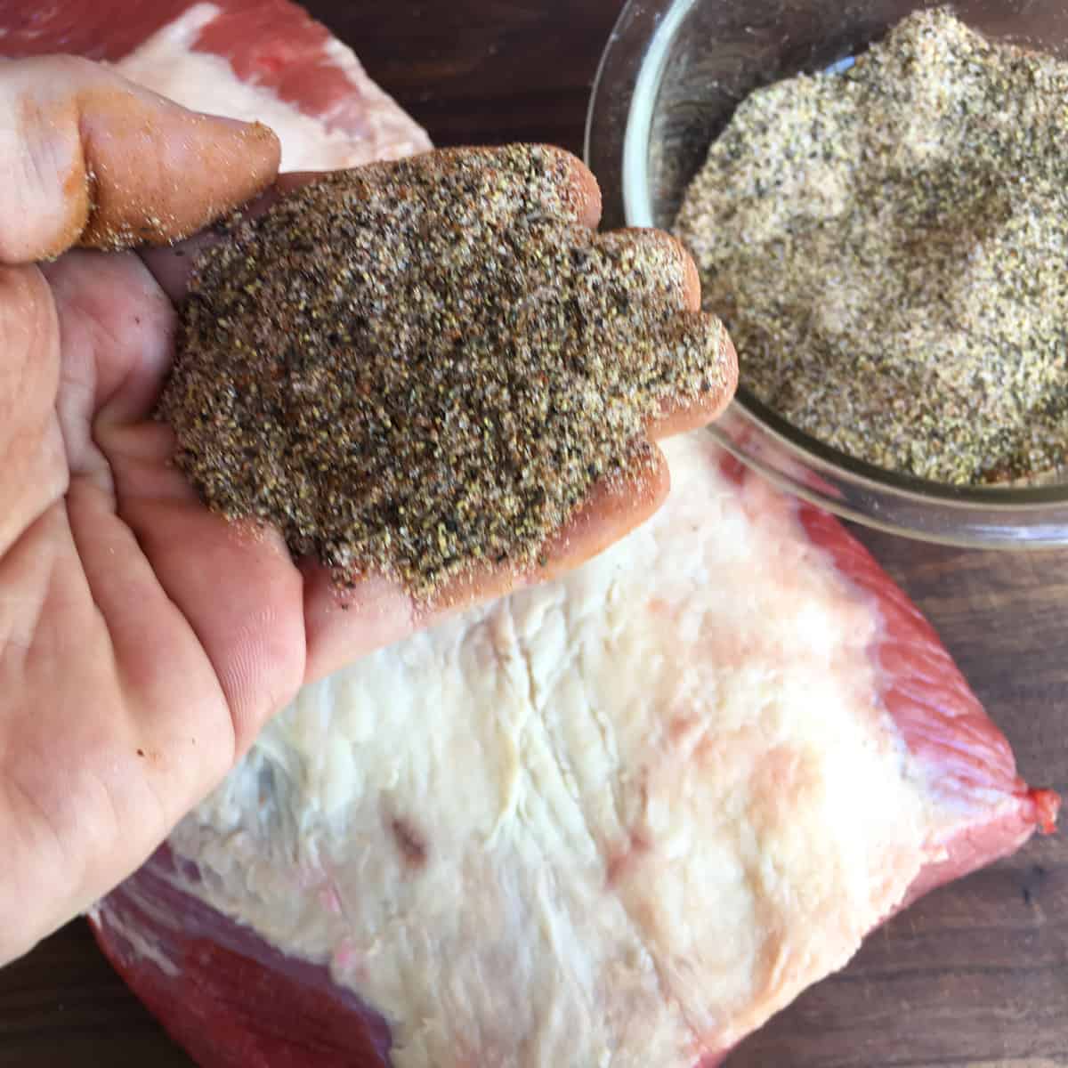 Holding a blend of spices over a roast.