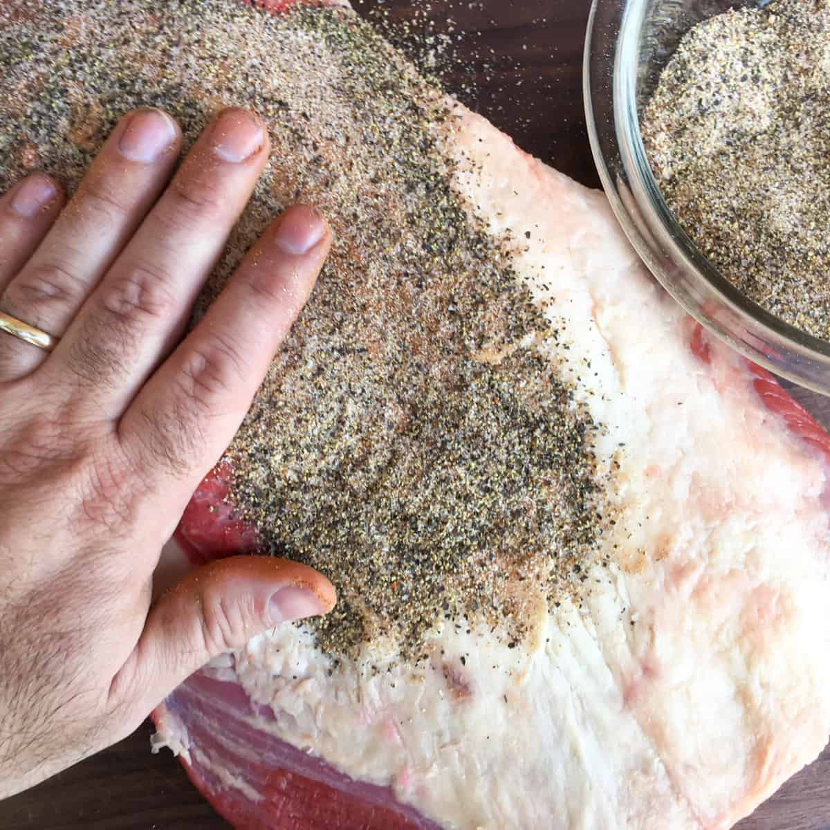 Rubbing some spices on a piece of beef.