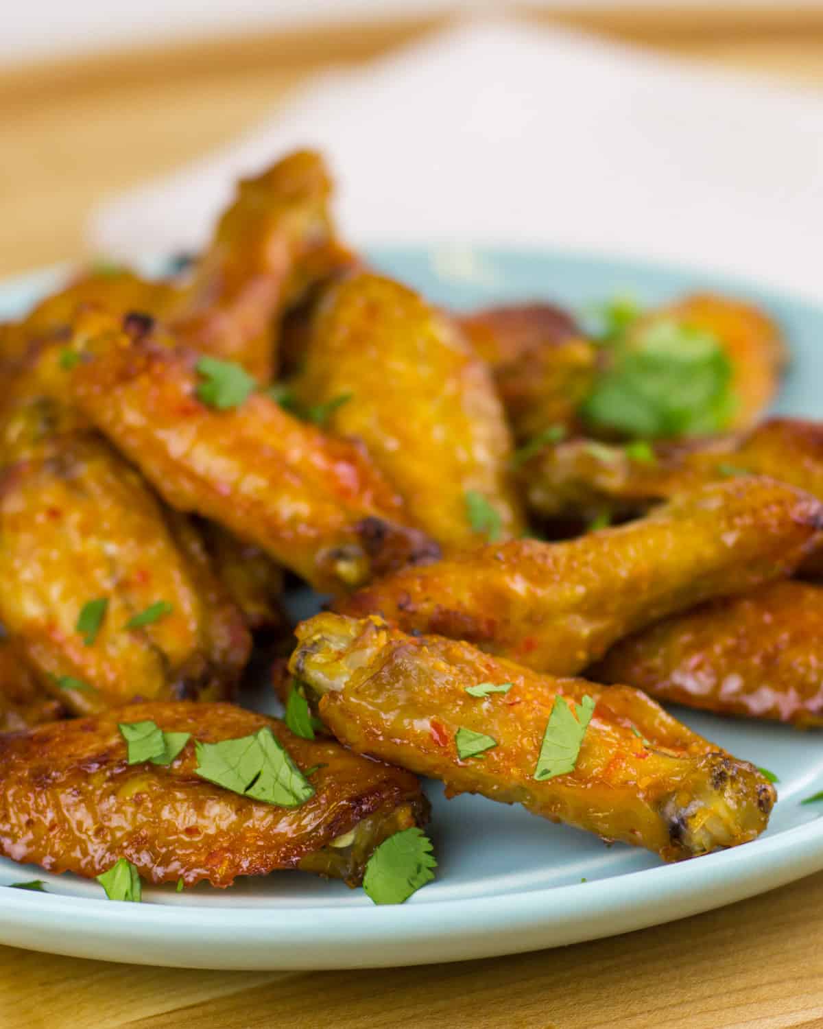 Close up picture of sticky baked wings on a blue plate.
