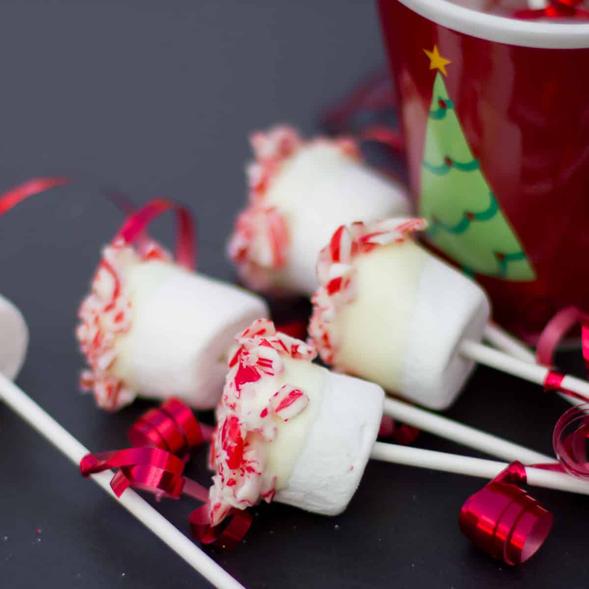 Marshmallow pops next to a coffee mug.