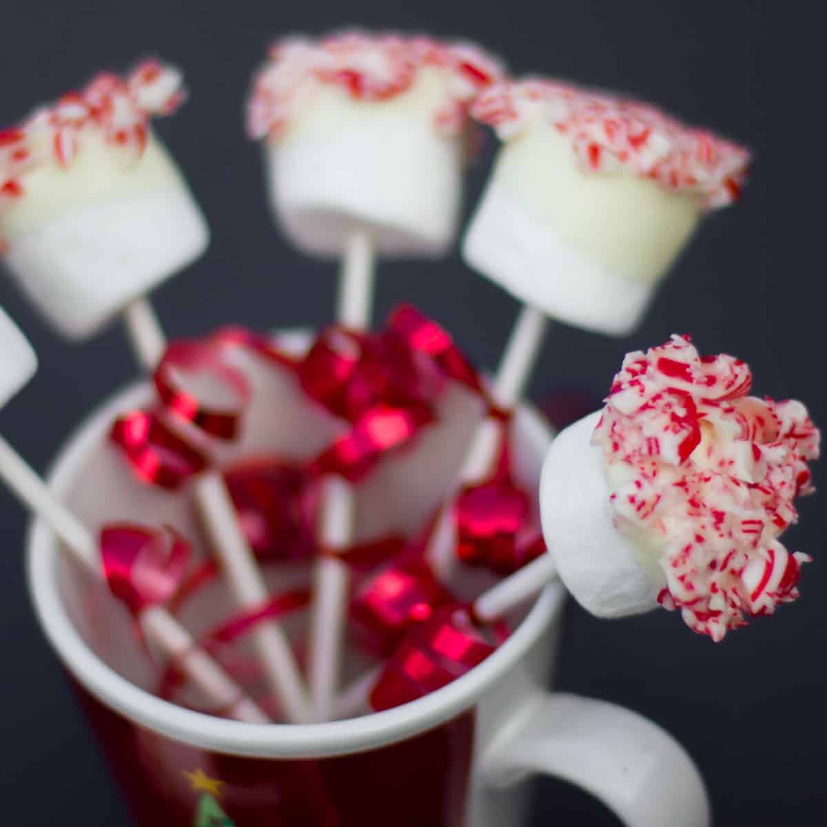 Marshmallow pops in a coffee mug.
