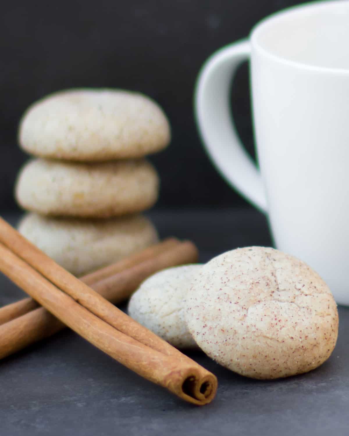 Cookies next to a coffee mug and cinnamon sticks.