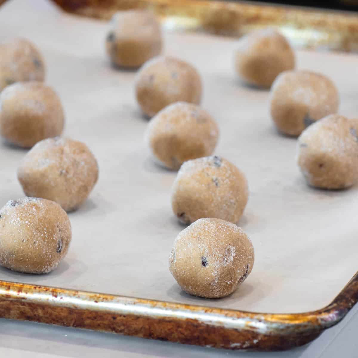 Cookie dough balls on a baking sheet lined with parchment paper.
