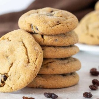 A stack of cookies surrounded by raisins.