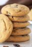 A stack of cookies surrounded by raisins.