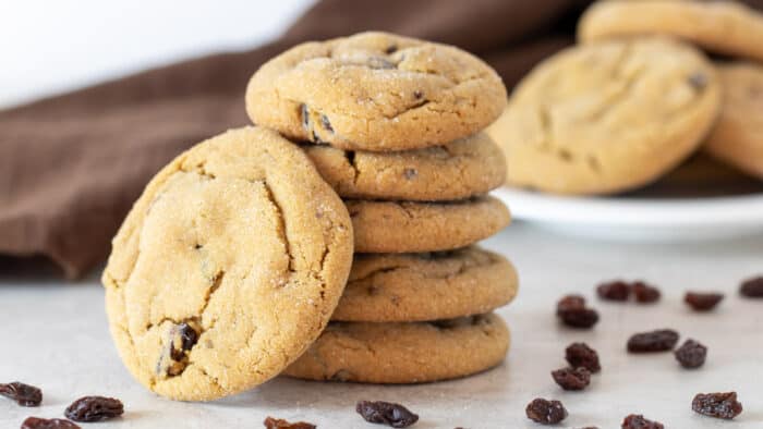 A stack of cookies surrounded by raisins.