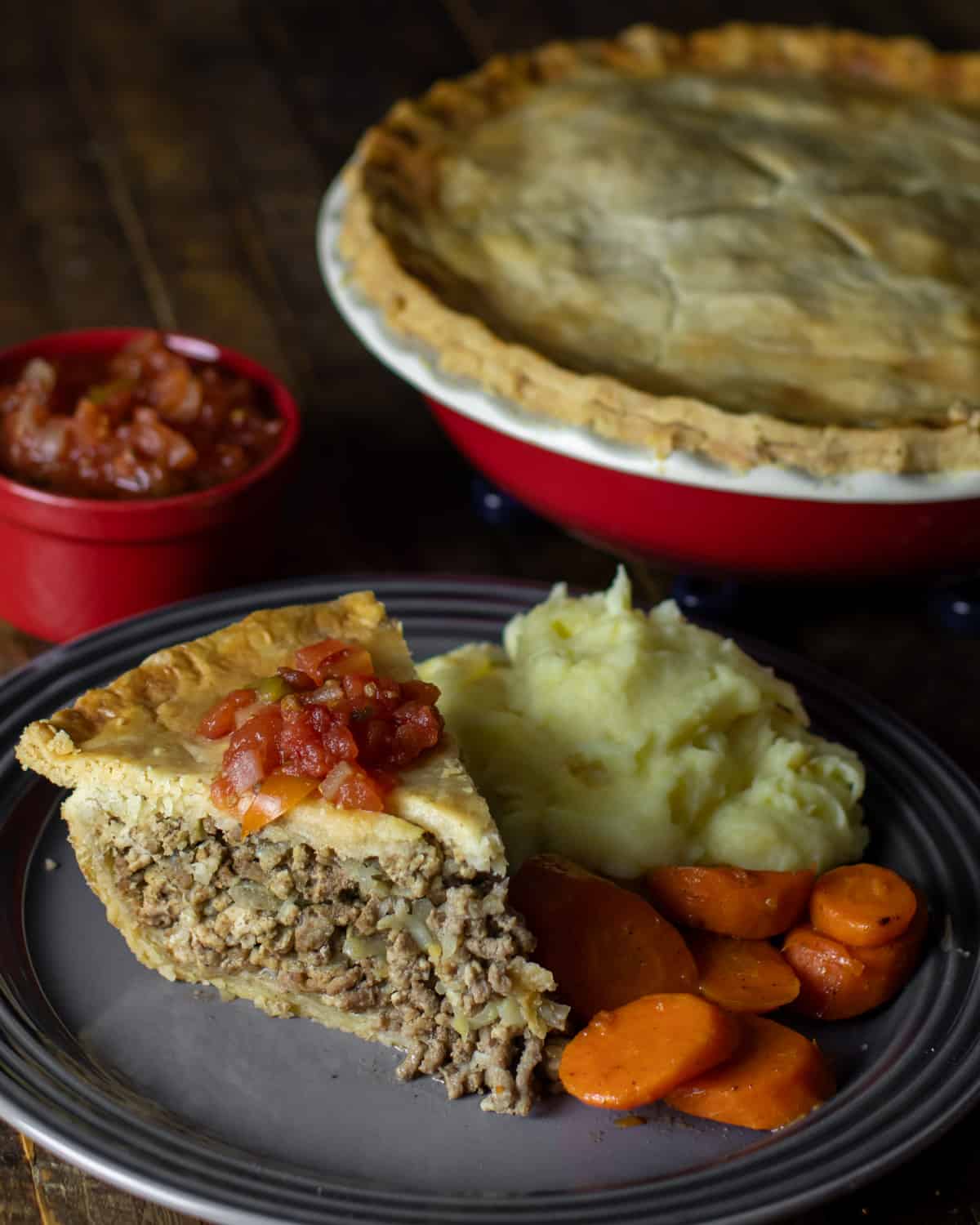 Overhead plate with a slice of meat pie, mashed potatoes and carrots.