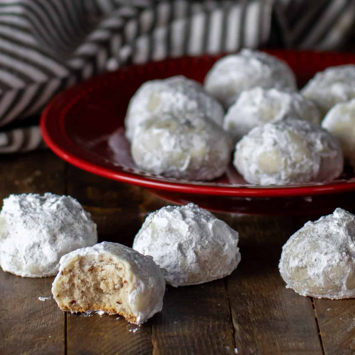 A red plate with round cookies coated in icing sugar.