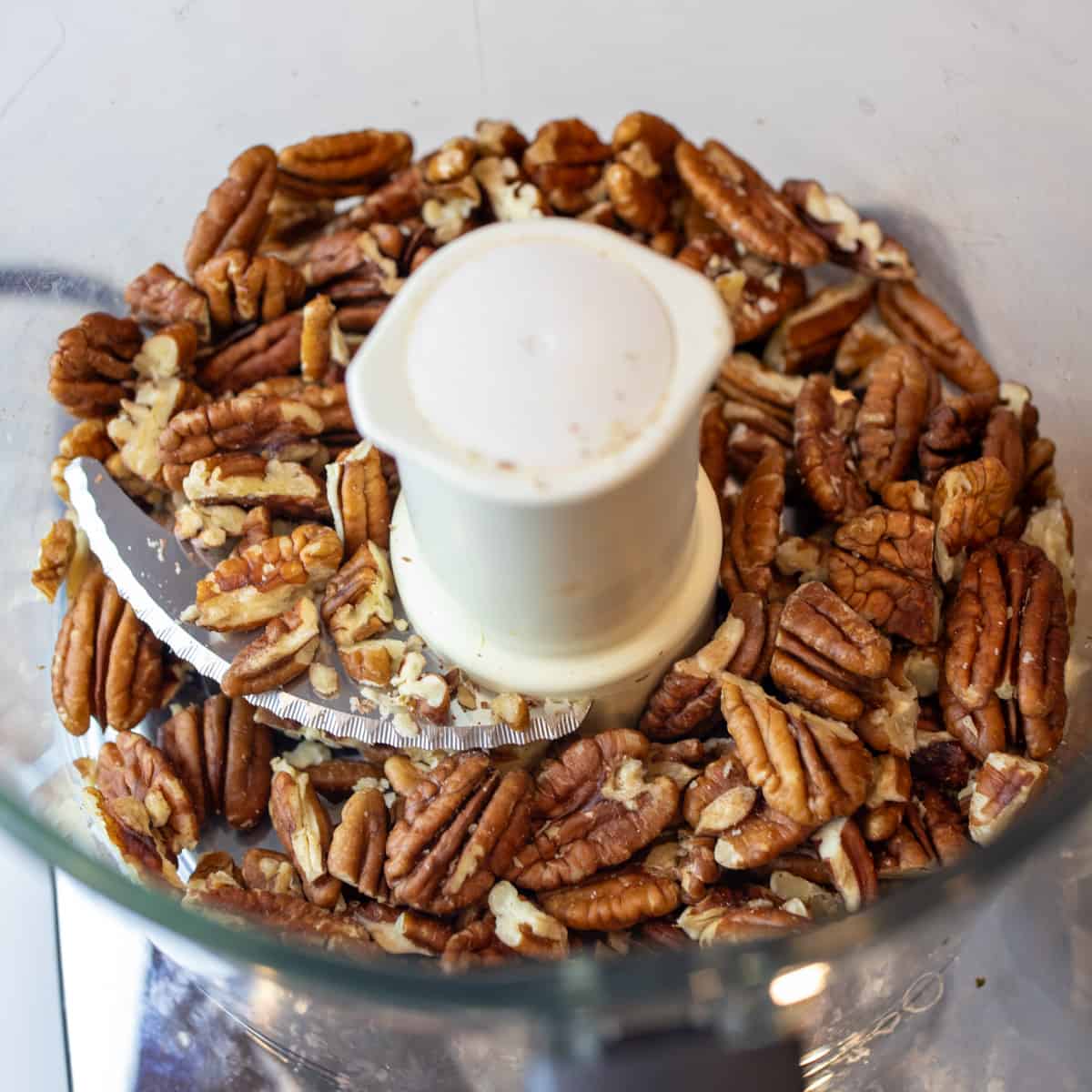 Pecans placed in a food processor ready to be ground.
