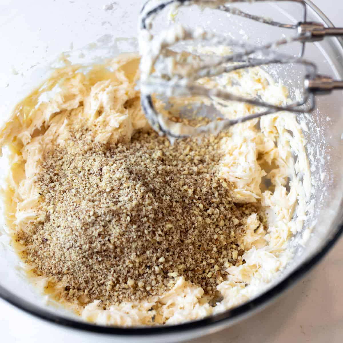 A mixing bowl with cookie dough and ground nuts.
