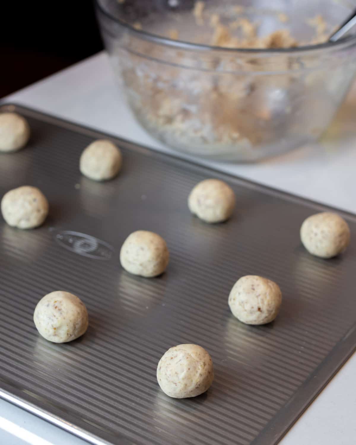 Cookie dough rolled into balls on a cookie sheet.