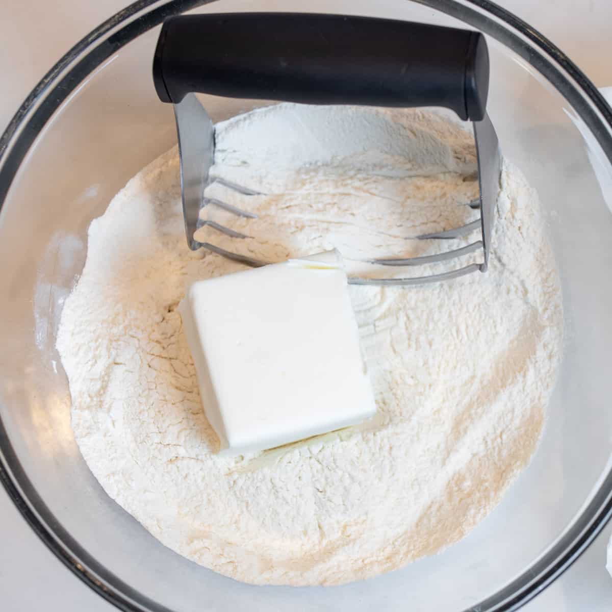 A glass bowl of flour and vegetable shortening.