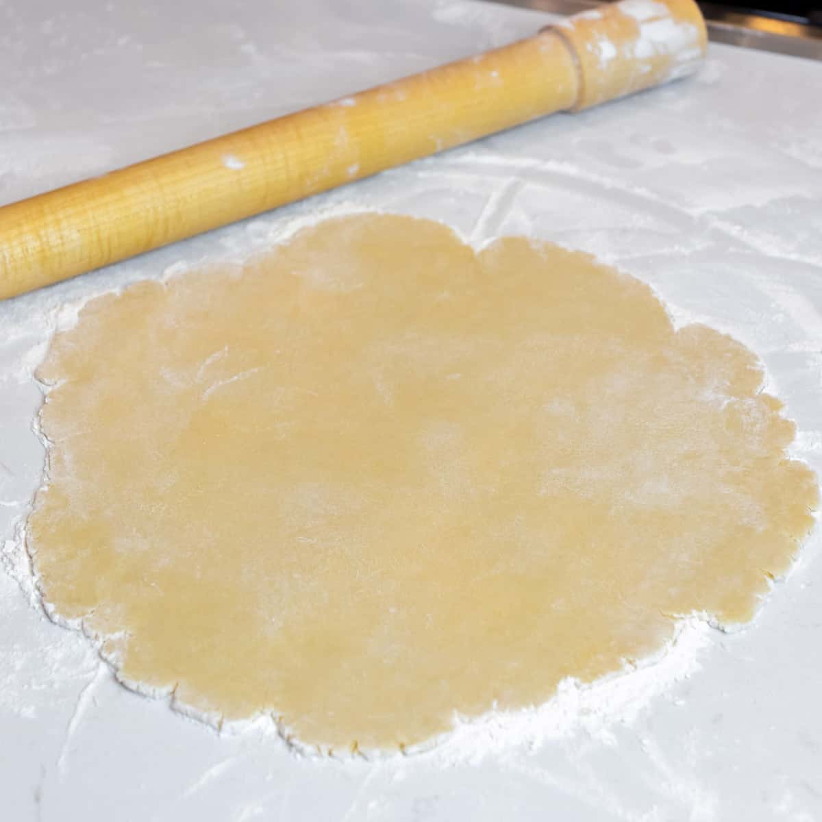 Pie crust dough rolled out on a floured surface.