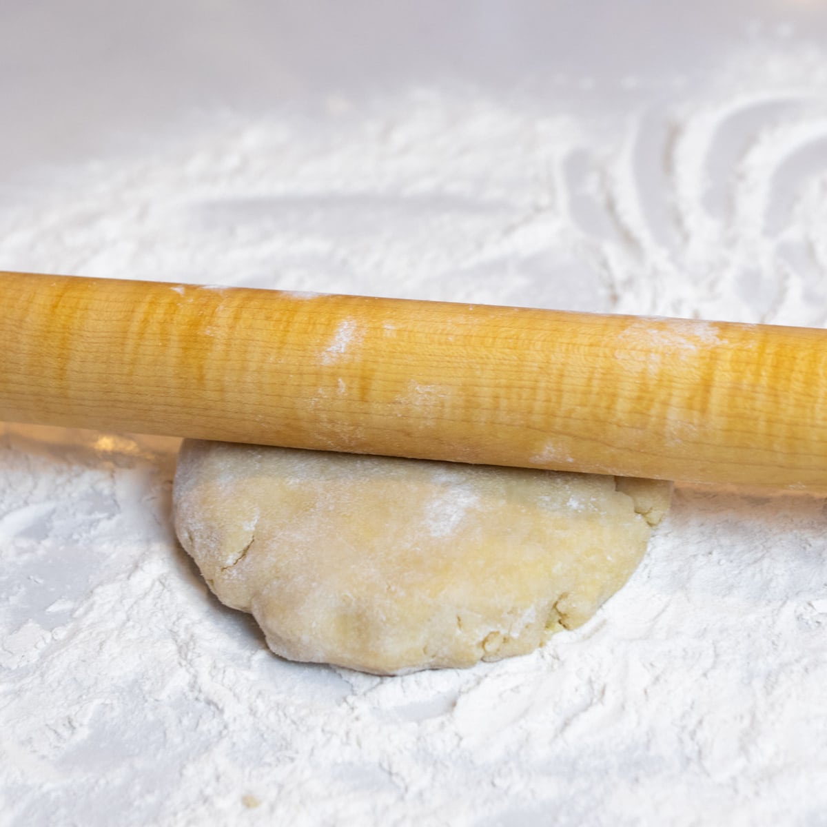 Rolling pin on a circle of pie dough.