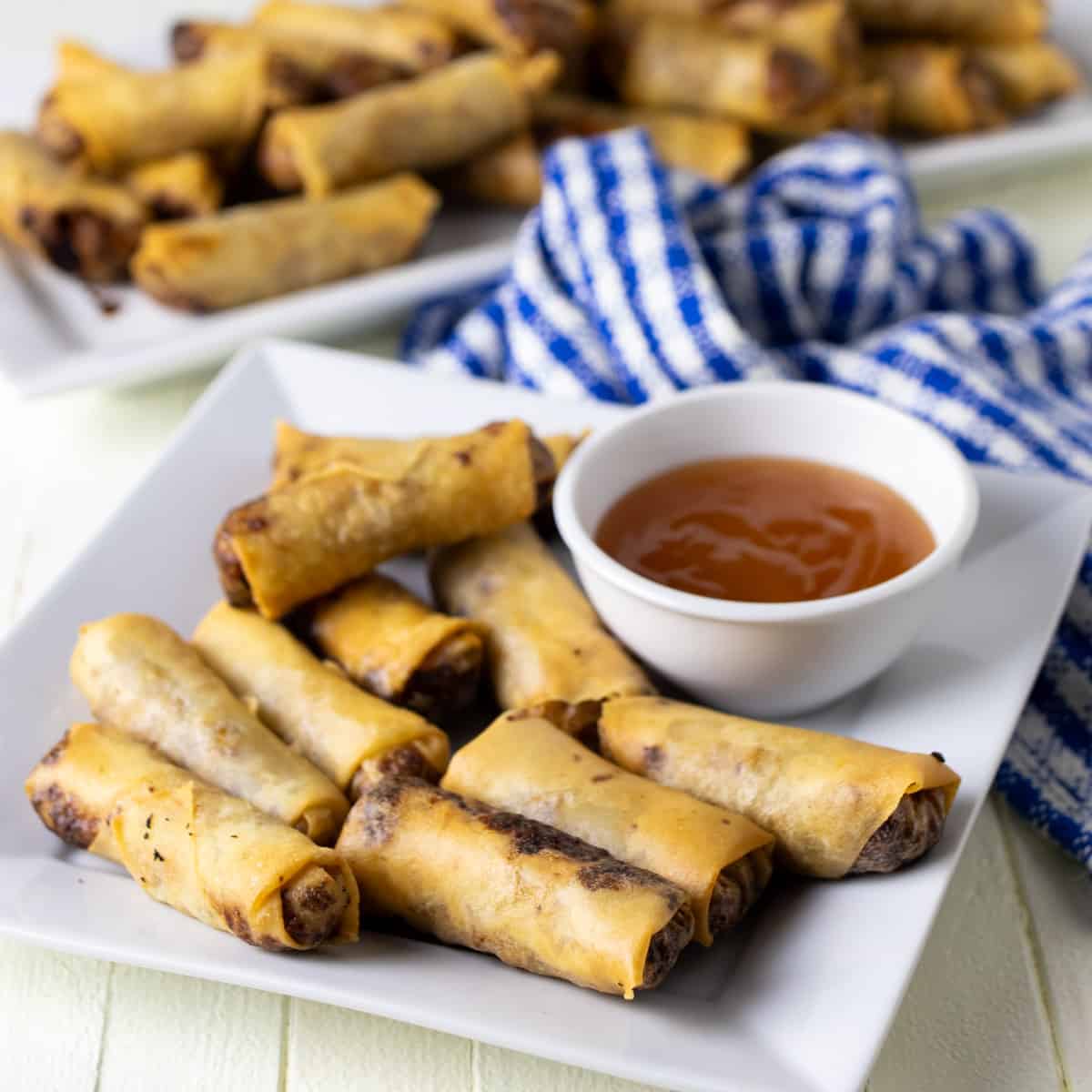 Lumpia on a plate with dipping sauce.