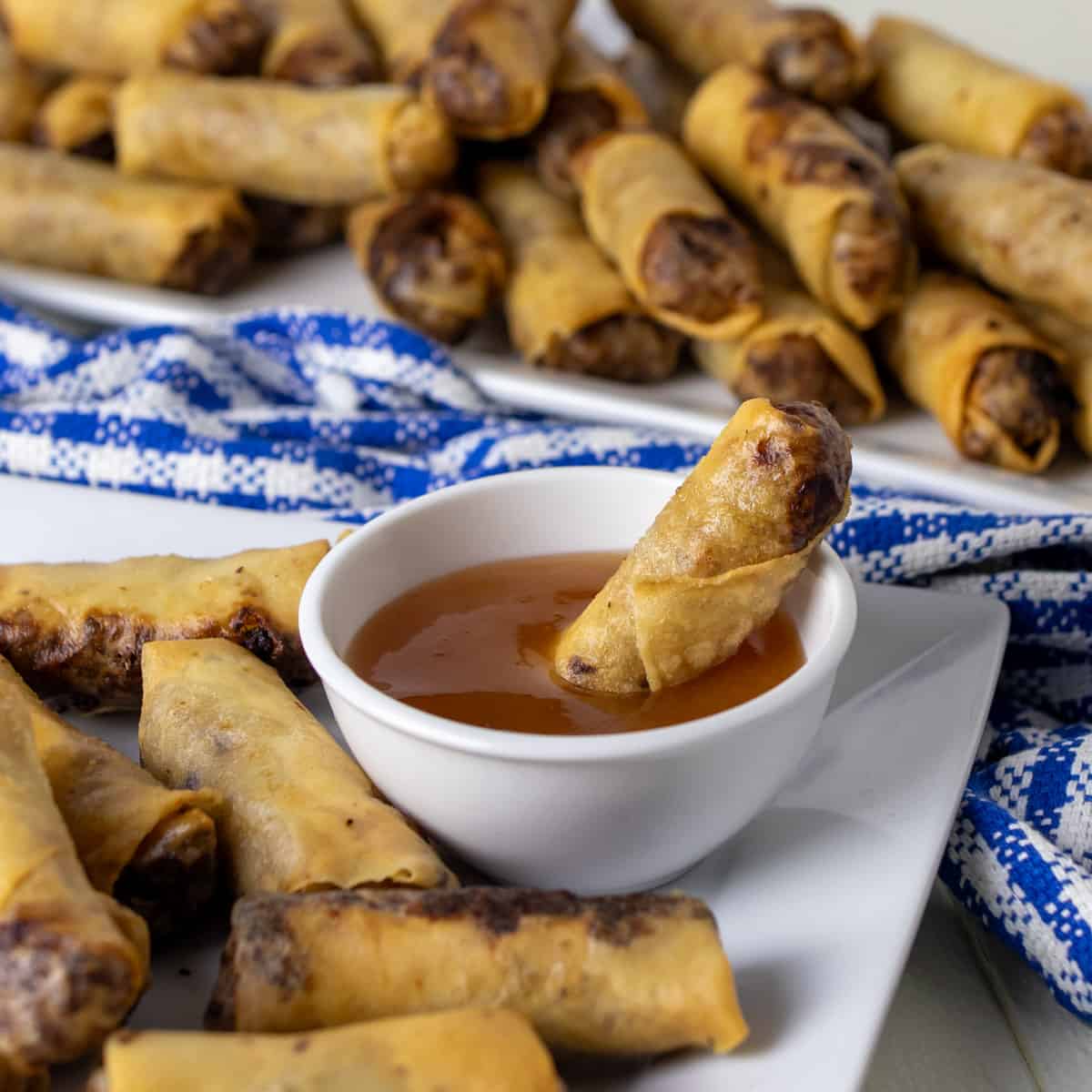 A spring roll dipped in a bowl of plum sauce.
