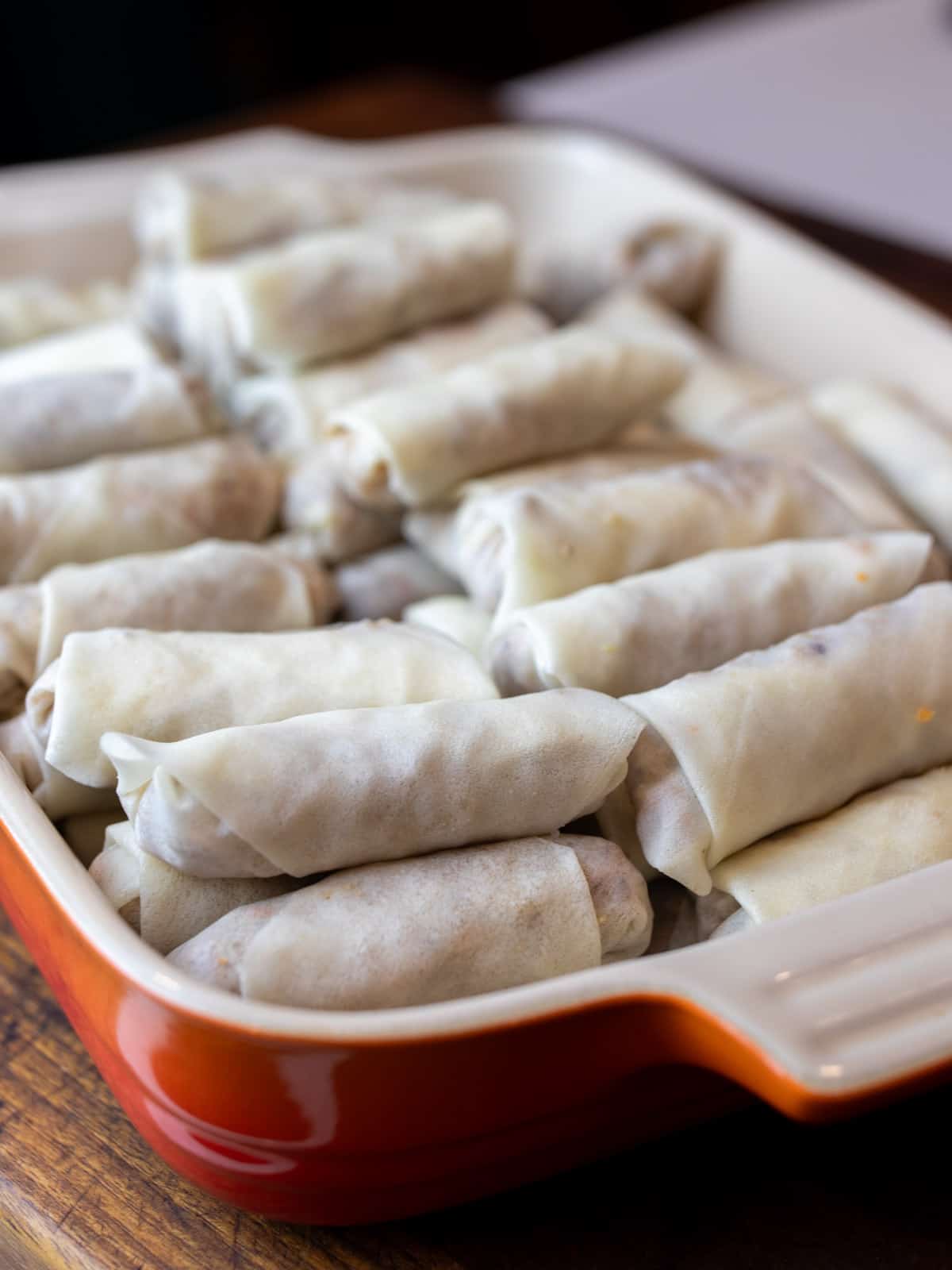 A stack of uncooked lumpia in a rectangular dish.