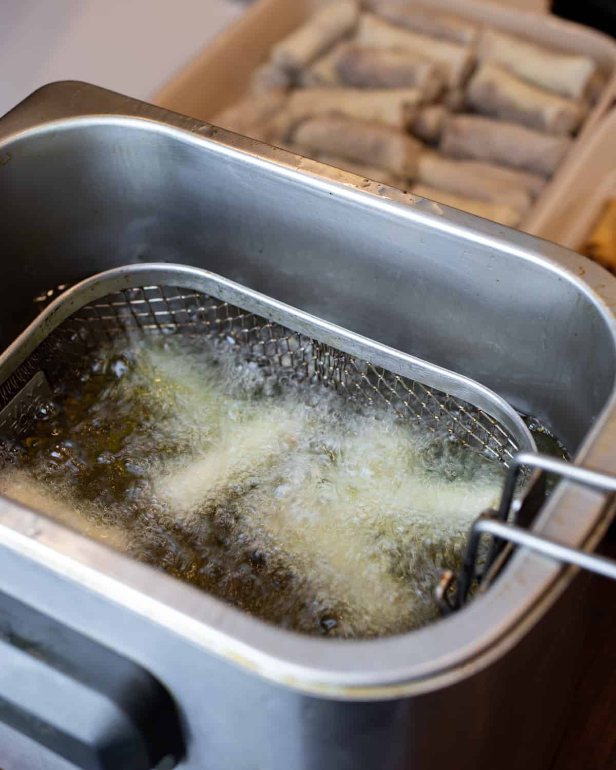 Spring rolls being fried in hot oil.